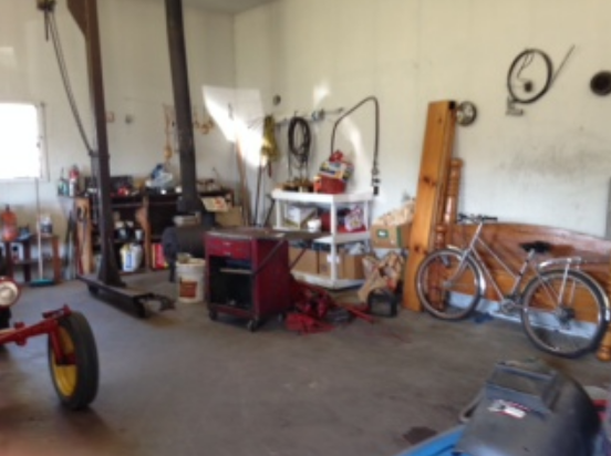 Cluttered garage workshop with bikes and tools before