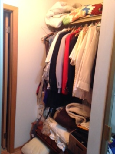 Cluttered closet full of clothes before