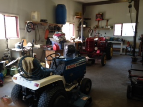 Garage with riding mowers and equipment before