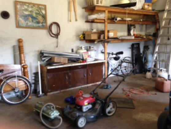 Cluttered garage with vintage tools and bikes before